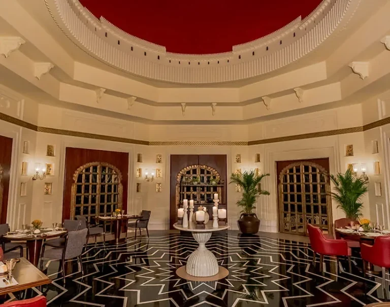 Elegant dining room with traditional architectural details, patterned flooring and refined table settings at The Oberoi Udaivilas Udaipur.