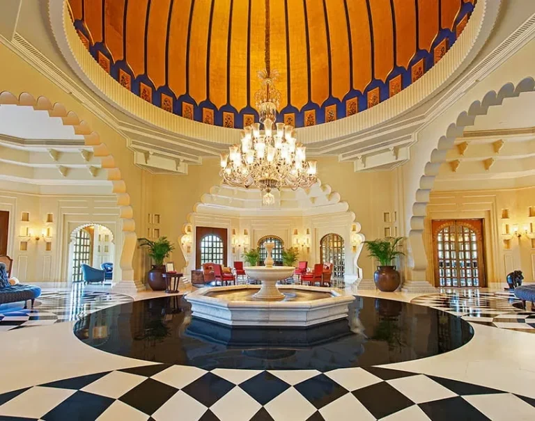 Grand palace-style lobby at The Oberoi Udaivilas Udaipur, featuring a domed ceiling, chandelier, decorative arches and marble flooring.