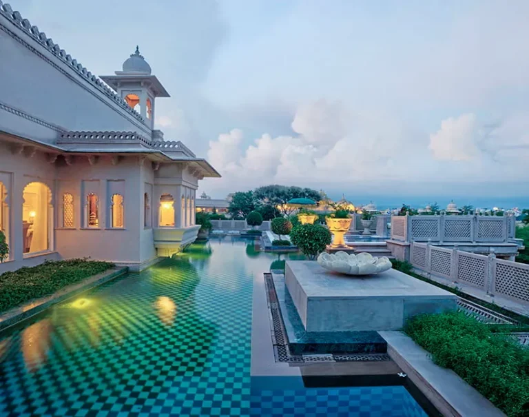 Circular dining room at The Oberoi Udaivilas, featuring decorative arches, a central table and elegant palace-style furnishings.