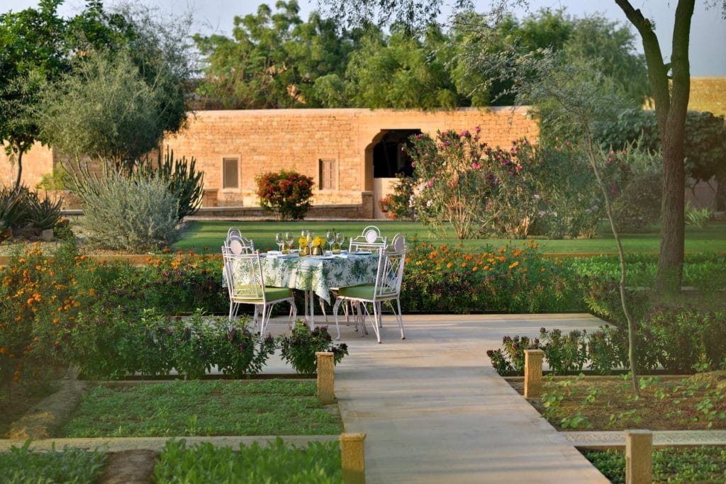 Lush garden with outdoor dining and sandstone cottages at Suryagarh Jaisalmer – romantic destination wedding venue Rajasthan