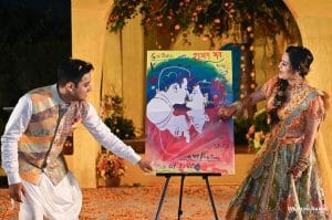 Couple unveiling a live painted portrait on stage at their Sangeet in Udaipur, a one-of-a-kind wedding entertainment idea by Desert Pearl Weddings
