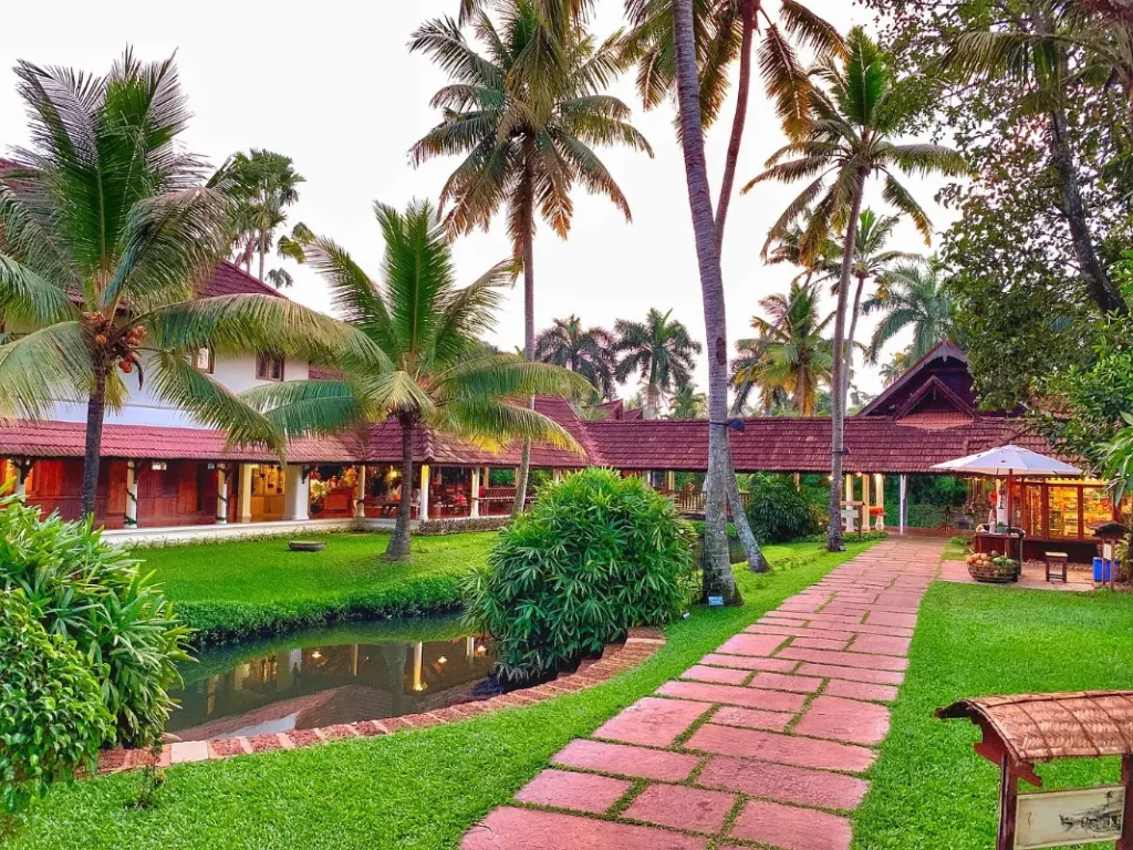 Garden pathway with canal and heritage buildings at dusk at Kumarakom Lake Resort