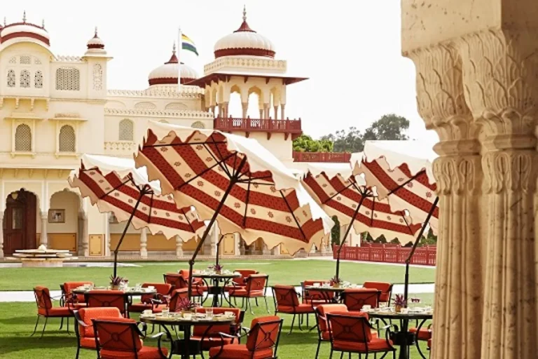 Striped umbrella lawn seating with palace turrets at Rambagh Palace, Jaipur