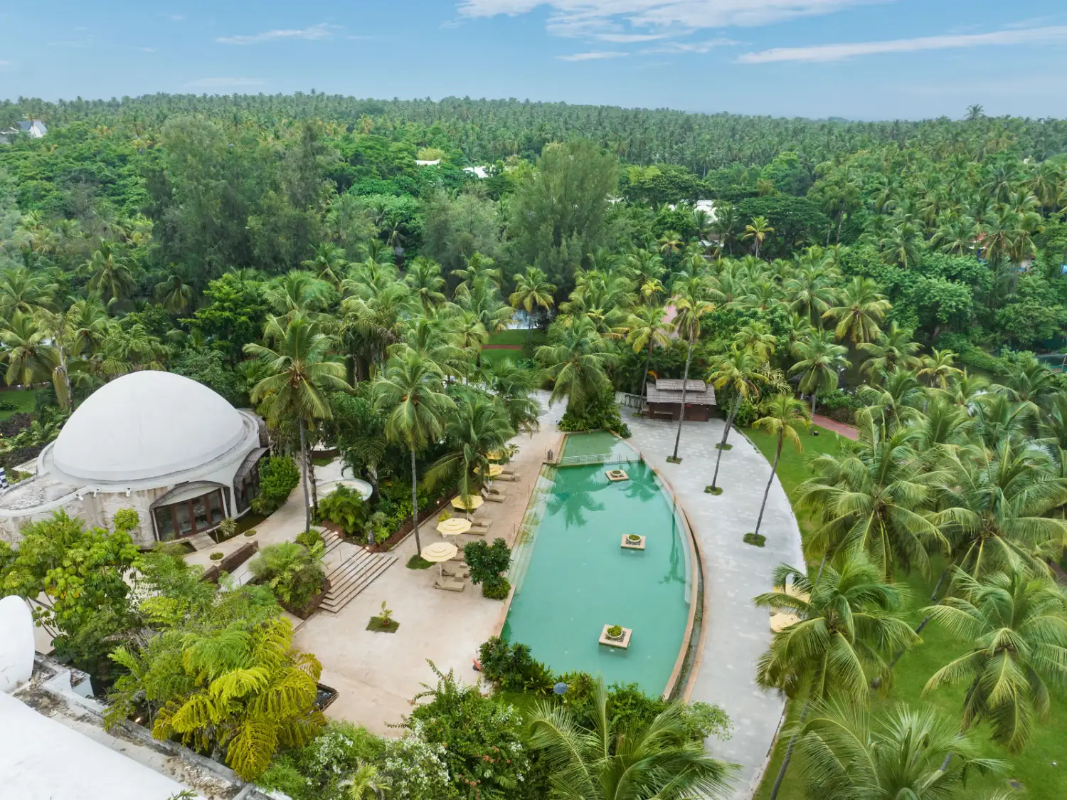 Aerial view of Taj Bekal's iconic domed pavilion and pool amid palm forest