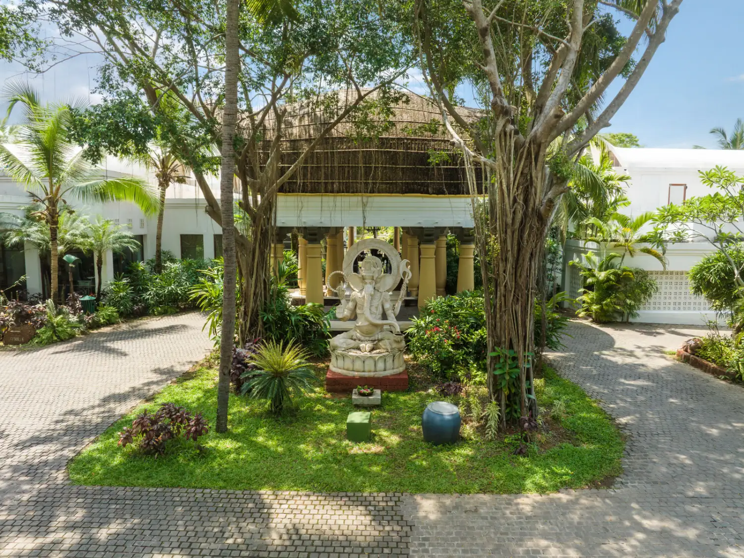 Ganesha shrine under banyan tree and thatched pavilion at Taj Bekal Resort & Spa