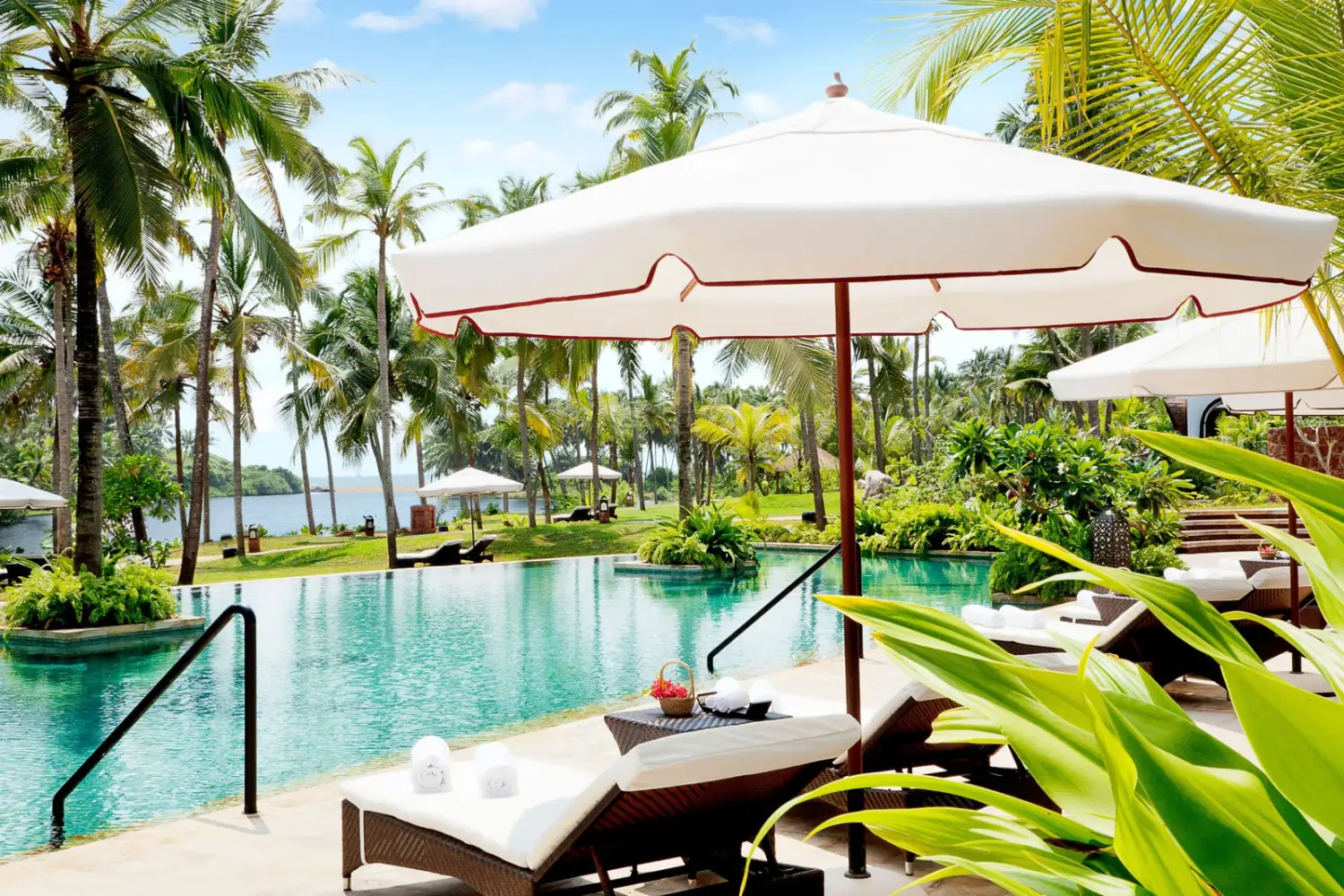Poolside loungers overlooking backwater and palm grove at Taj Bekal Resort & Spa