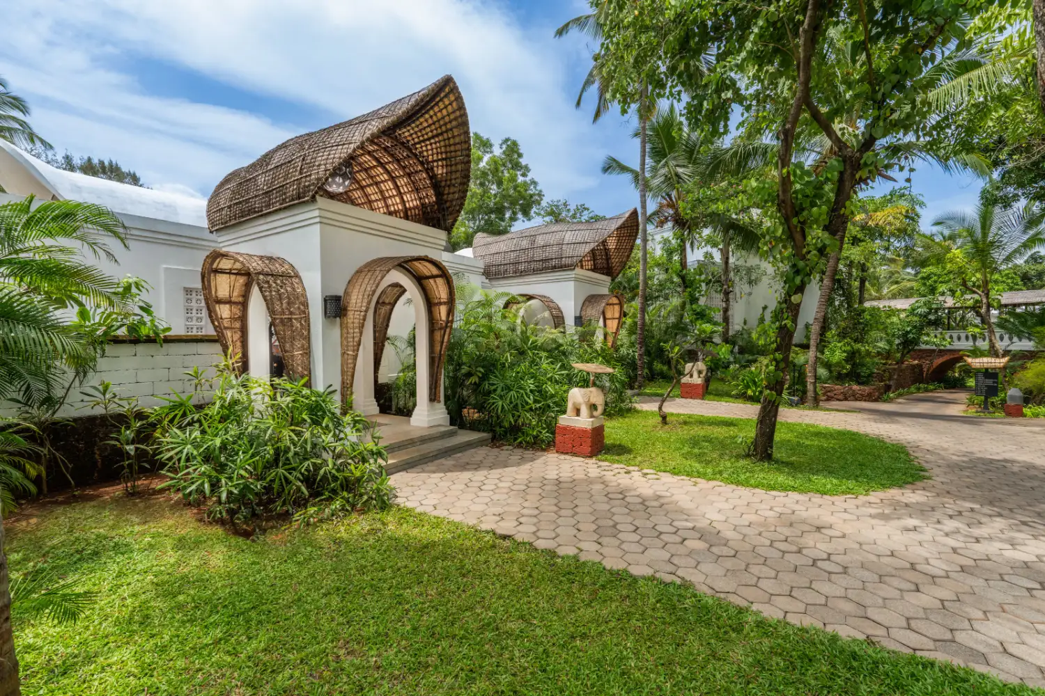 Conical thatched-roof villa entrance with garden pathway at Taj Bekal Resort & Spa