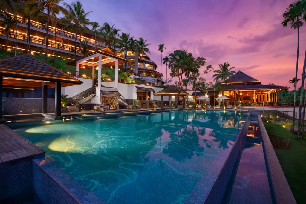 Infinity pool at twilight with hillside guest wing at Taj Wayanad Resort & Spa
