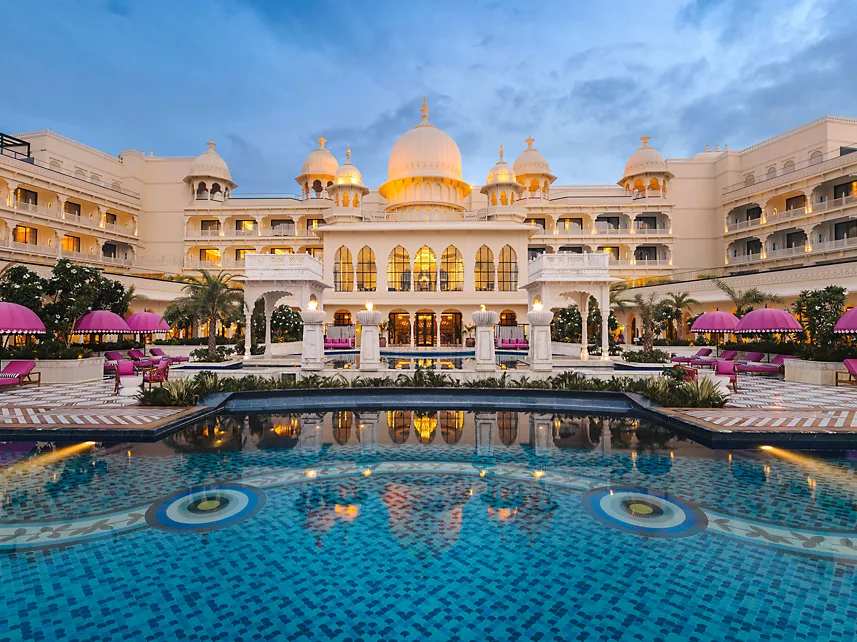 Illuminated domed palace facade reflected in pool at dusk at Fairmont Udaipur Palace Udaipur