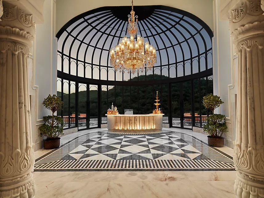 Glass dome conservatory bar with crystal chandelier and marble floor at Fairmont Udaipur Palace
