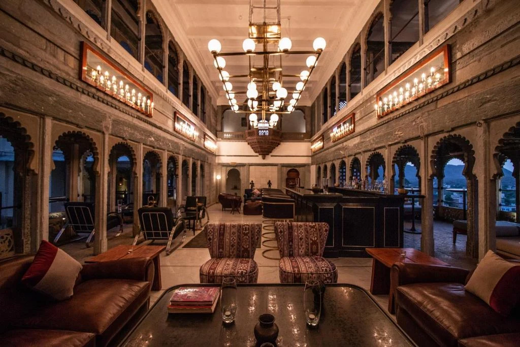 Grand double-height bar and lounge with carved arched galleries and chandelier at RAAS Devigarh Udaipur
