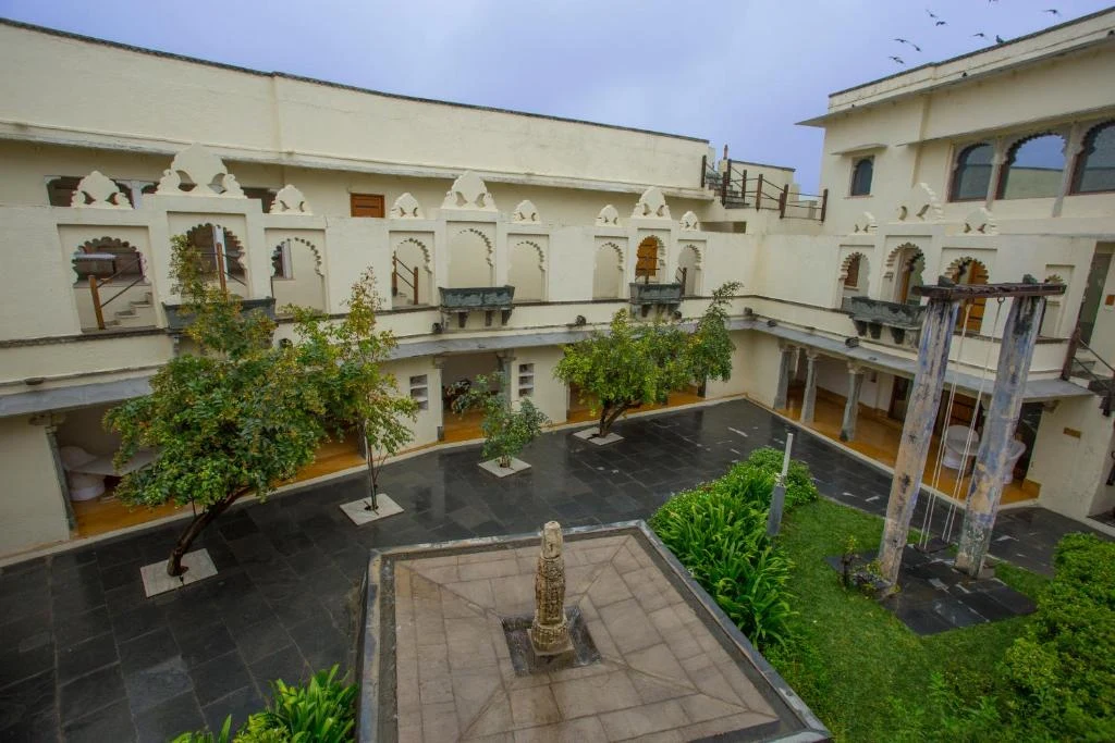 Heritage inner courtyard with arched galleries trees and traditional swing at RAAS Devigarh Udaipur
