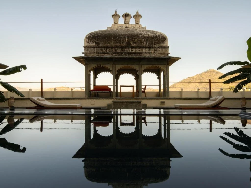 Heritage pool with ancient carved chattri reflected in dark water at RAAS Devigarh Udaipur