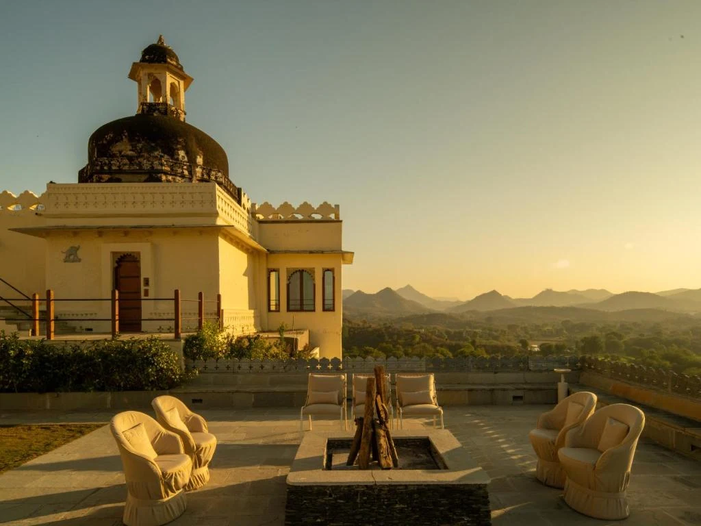Rooftop terrace firepit seating with domed cupola and Aravalli sunset panorama at RAAS Devigarh Udaipur
