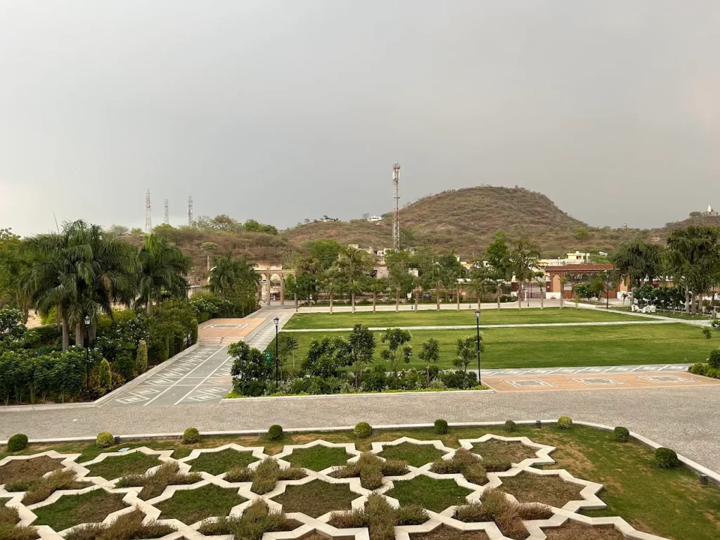 Expansive Raj Van manicured lawn with palm-lined avenue and Aravalli hills at Taj Lalit Bagh Udaipur