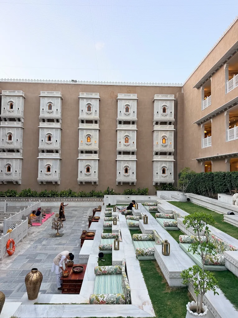 Stepwell courtyard with tiered marble seating and floral cushions set for pre-wedding function at Taj Lalit Bagh Udaipur
