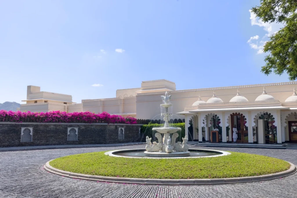Marble tiered fountain in circular driveway forecourt with bougainvillea wall and domed entrance at Trident Udaipur