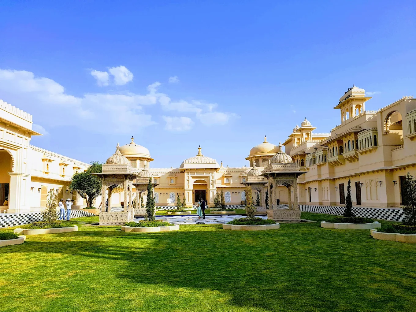 Sunlit wedding ceremony lawn with carved domed chattris and palace facade at Trident Udaipur