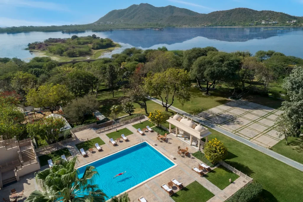 Aerial view of Trident Udaipur pool terrace and chattri pavilion with Lake Pichola and Aravalli mountains backdrop