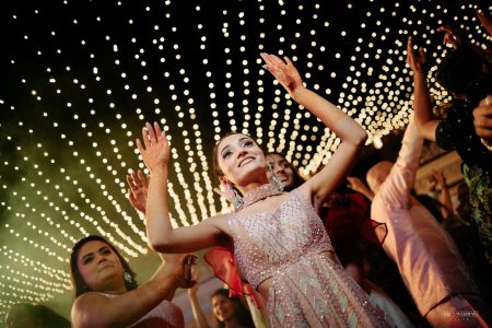 Bride dancing under string lights at a Mehendi night at The Leela Palace Jaipur, a vibrant Sangeet photography moment by Desert Pearl Weddings
