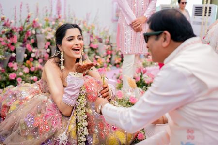 Bride laughing while receiving a rose during Haldi function at Fairmont Jaipur destination wedding