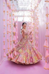 Bride spinning in colorful lehenga inside pink tassel corridor at Fairmont Jaipur Haldi ceremony