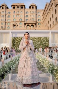 Bride in pale pink heavy lehenga walking down mirror aisle at outdoor wedding ceremony Fairmont Jaipur