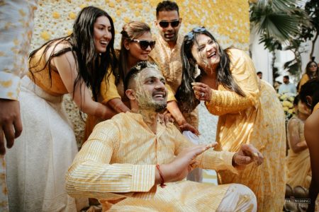 Groom laughing with family during Haldi ceremony at The Leela Palace Jaipur, a joyful candid moment from a destination wedding by Desert Pearl Weddings
