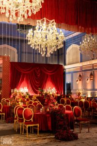 Indoor Sangeet ballroom with red velvet drapes and crystal chandeliers at Fairmont Jaipur