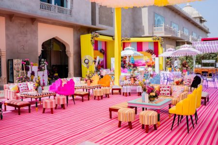 Bright yellow and pink outdoor Mehendi decor setup with striped carpet at Fairmont Jaipur