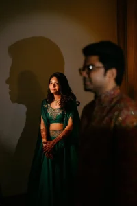 Bride in teal cape lehenga and groom in printed sherwani walking through sparkler tunnel entry at cocktail night, destination wedding in Rajasthan