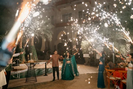 Couple making grand entrance through sparkler tunnel at cocktail night during luxury destination wedding in Rajasthan, planned by Desert Pearl Weddings