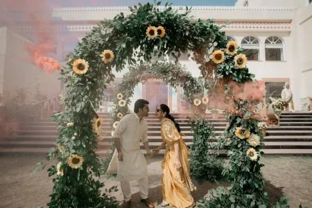 Bride and groom sharing an intimate moment under sunflower arch with colored smoke at haldi ceremony, destination wedding in Rajasthan by Desert Pearl Weddings