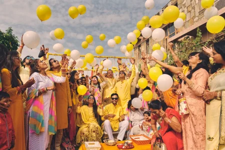 Bride groom and family releasing yellow and white balloons during joyful haldi ceremony celebration at outdoor destination wedding in Rajasthan