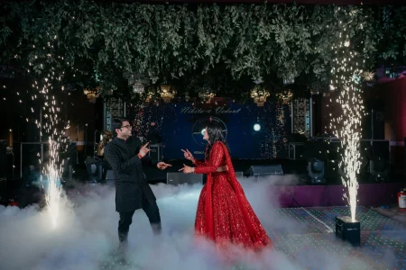 Bride and groom dancing at Nikita Vedant sangeet night with cold pyro fountains under hanging greenery canopy, destination wedding in Rajasthan by Desert Pearl Weddings